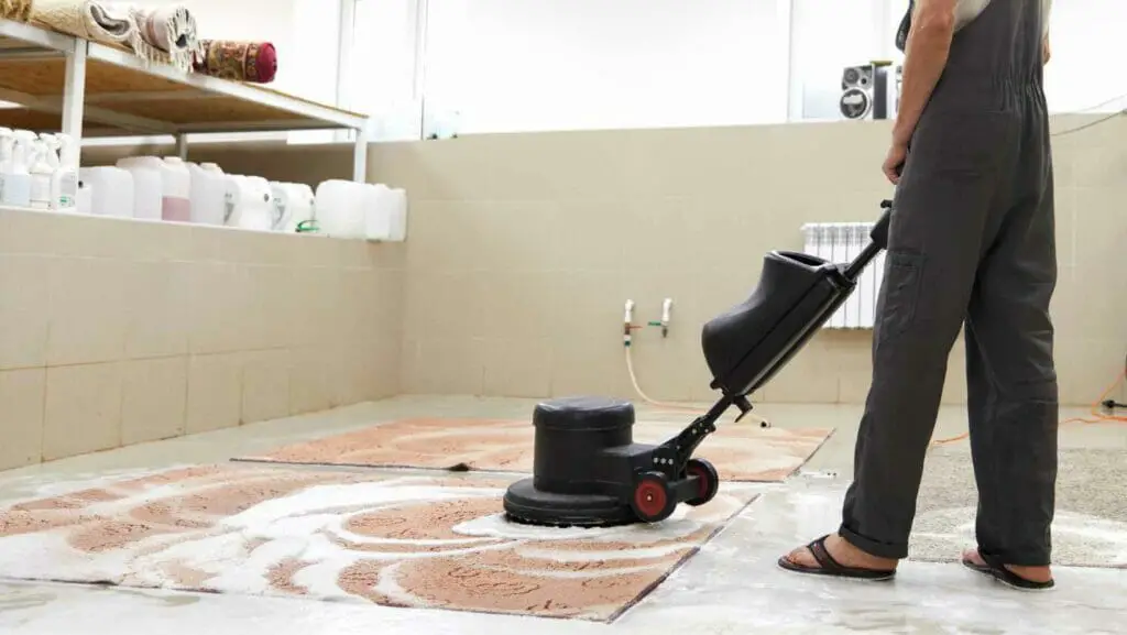 Photo of a professional carpet cleaner, cleaning a carpet with chemicals.
